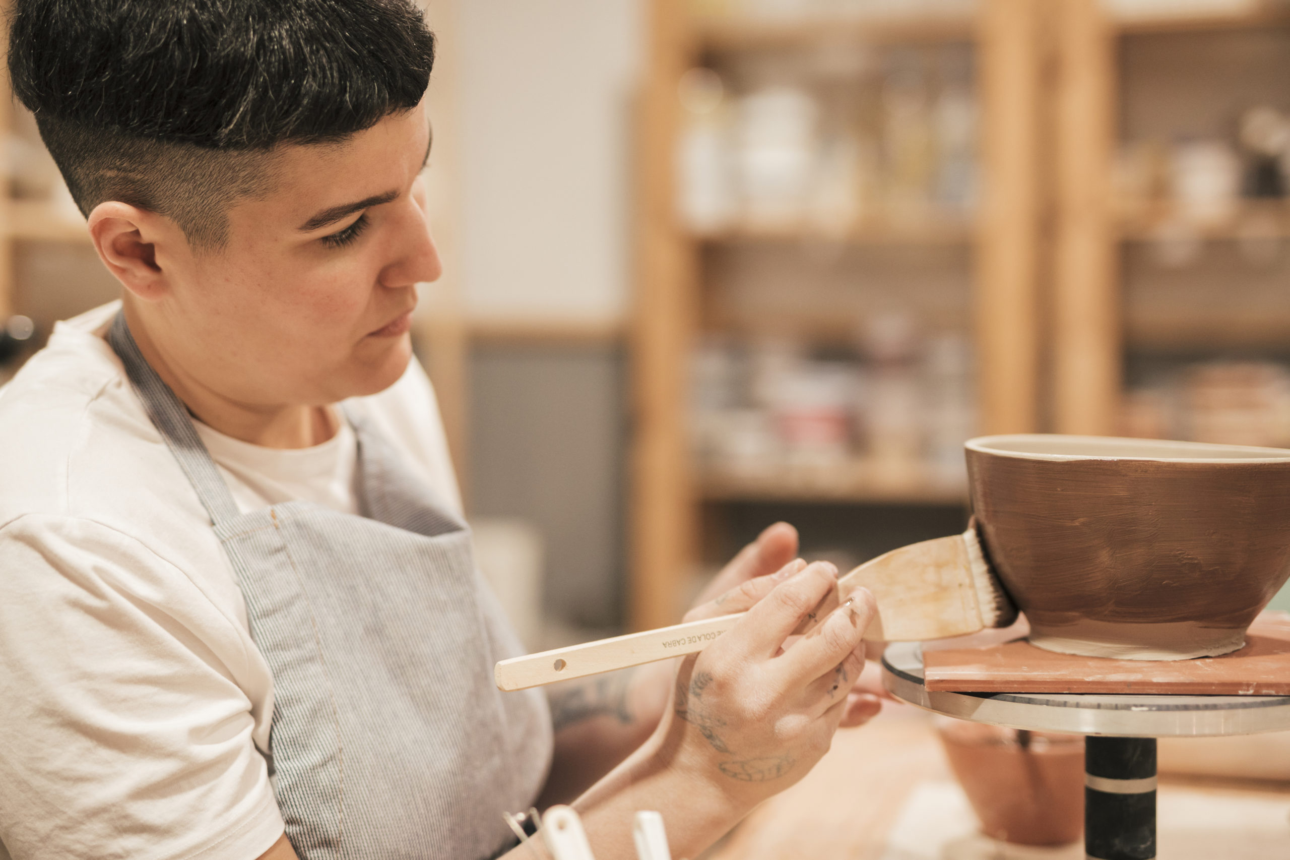 female-potter-painting-handmade-bowl-with-paintbrush-workshop